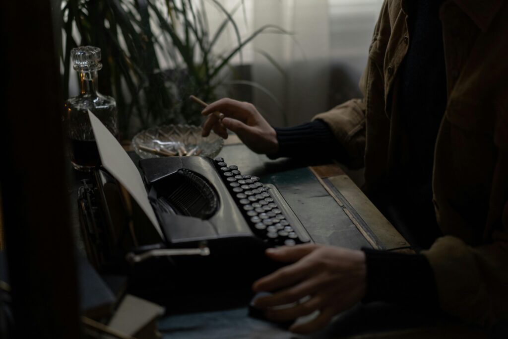 Moody scene of a person typing on a vintage typewriter, holding a cigarette.